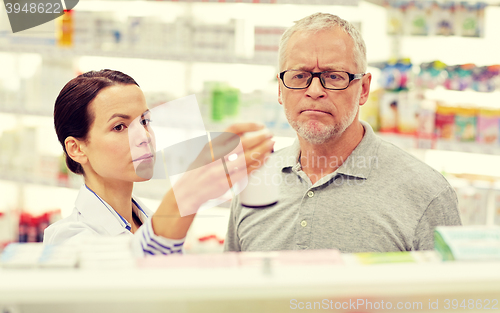 Image of pharmacist showing drug to senior man at pharmacy