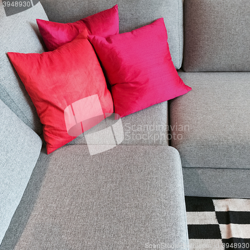 Image of Gray corner sofa with silky red cushions