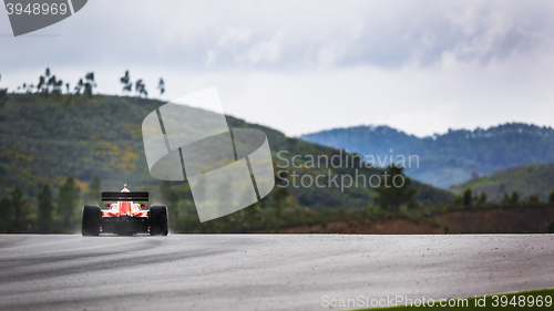 Image of Racing car in landscape of hills with spray of rain