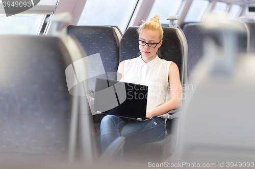 Image of Woman travelling by train working on laptop.