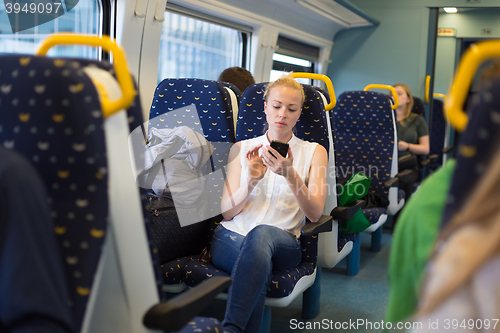 Image of Woman using mobile phone while travelling by train.