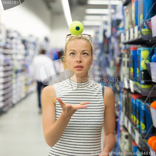 Image of Woman shopping tennis balls in sportswear store.