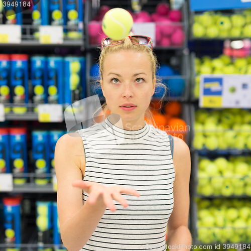 Image of Woman shopping tennis balls in sportswear store.