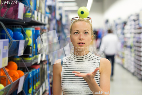 Image of Woman shopping tennis balls in sportswear store.