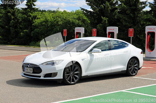 Image of White Tesla Model S Electric Car Leaves Charging Station 