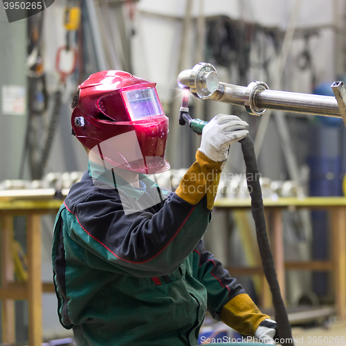 Image of Industrial worker welding in metal factory.