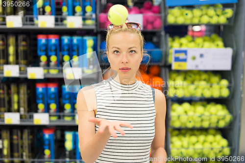 Image of Woman shopping tennis balls in sportswear store.