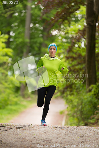 Image of Sporty young female runner in the forest. 