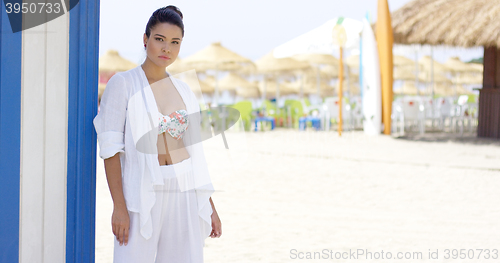 Image of Cheerful pretty woman in white robe on beach