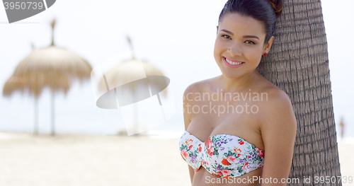 Image of Attractive young woman leaning on palm tree