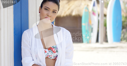 Image of Serious woman in bathing suit near surfboards