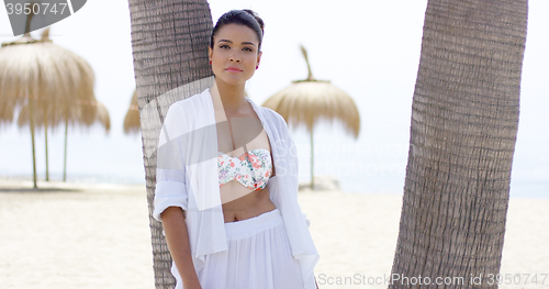 Image of Serious single woman leaning against palm tree