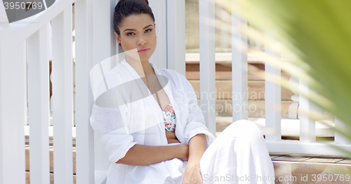 Image of Attractive young woman sitting near fence