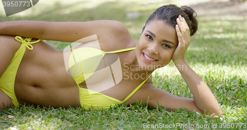 Image of Cute girl lies on grass in exotic park