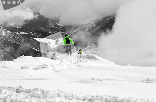 Image of Freeriders on off-piste slope and mountains in mist. Selective c