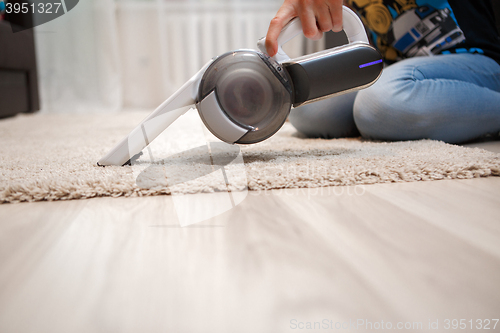 Image of Cleaning of rug in house portable rechargeable vacuum cleaner