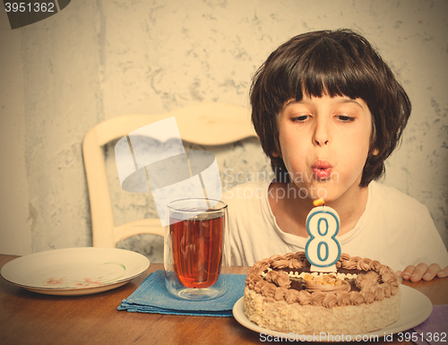 Image of boy blowing out candles on birthday cake