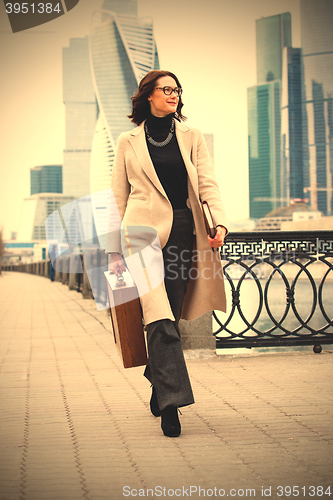 Image of woman with a wooden case in his hand in the bright coat