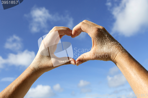 Image of Hands with sand show love symbol