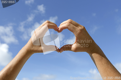 Image of Female hands shows love sign in the air