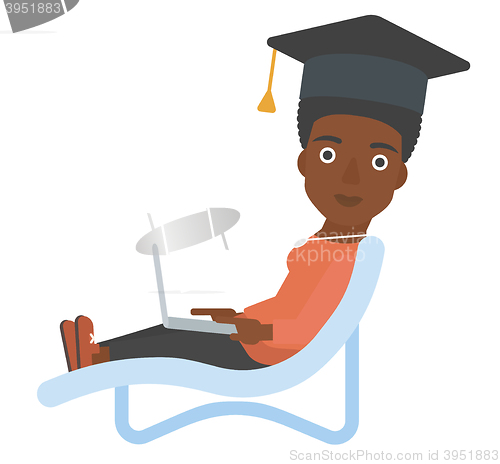 Image of Graduate lying in chaise lounge with laptop.