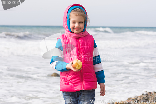 Image of Portrait of a five year old girl with an apple on the beach