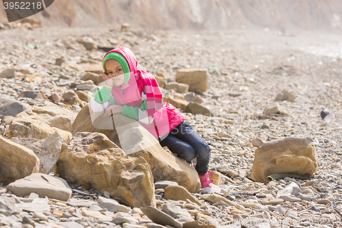 Image of A bored tired girl lay down on a big rock by the sea