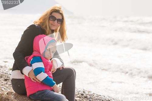 Image of My mother and five year old daughter sit on the beach and looked at turning frame