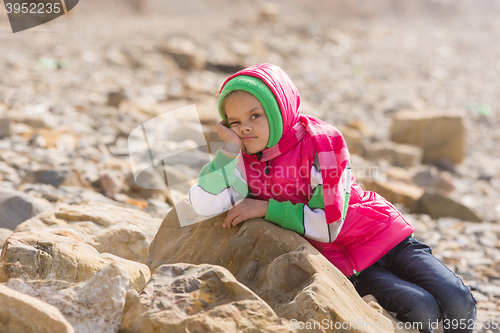 Image of Girl bored at the seaside in the offseason lay down on a big rock