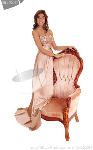 Image of Young woman standing on armchair.