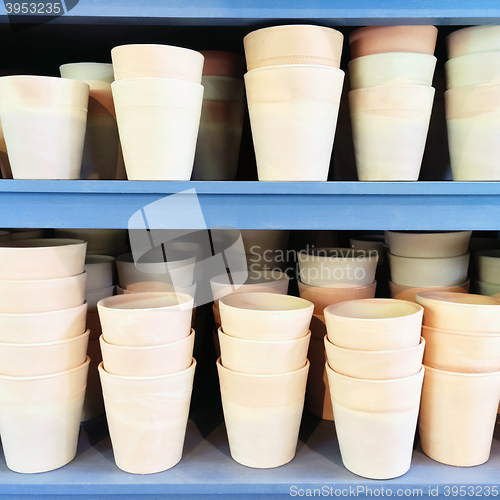 Image of Simple clay pots on blue shelves