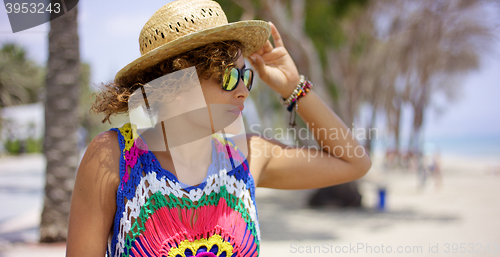 Image of Pretty woman in sunglasses adjusting hat