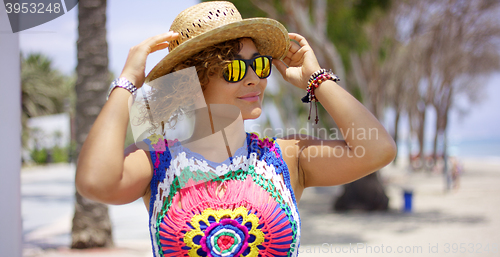 Image of Pretty woman in sunglasses adjusting hat