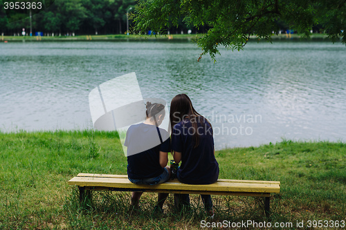 Image of Women sit on a bench and take selfies