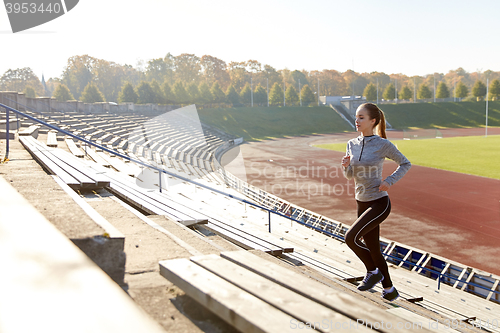 Image of happy young woman running upstairs on stadium