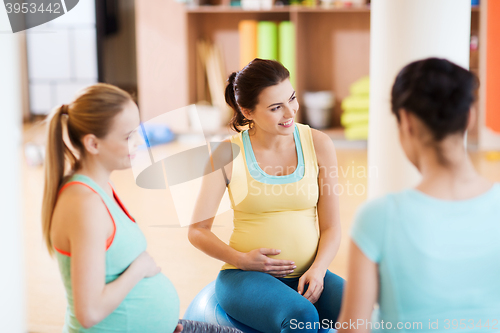 Image of happy pregnant women sitting on balls in gym