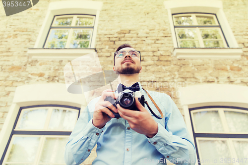 Image of happy young hipster man with film camera in city