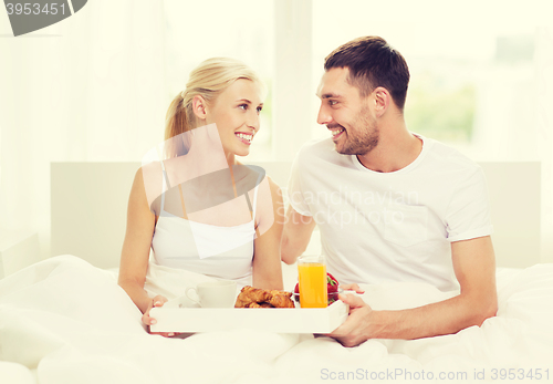 Image of happy couple having breakfast in bed at home
