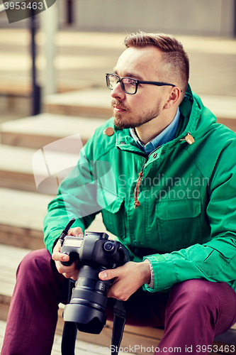 Image of young hipster man with digital camera in city