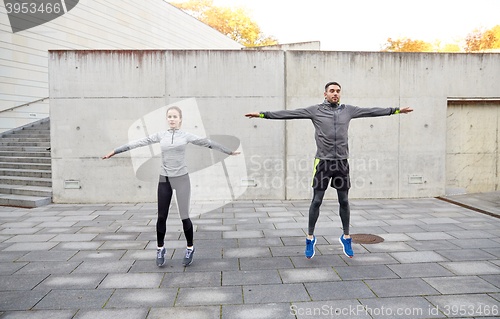 Image of happy man and woman jumping outdoors