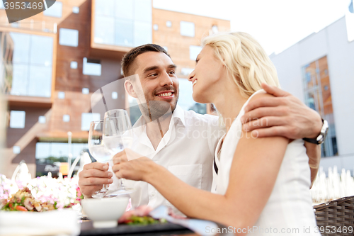 Image of happy couple drinking wine at open-air restaurant