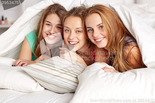 Image of happy young women in bed at home pajama party