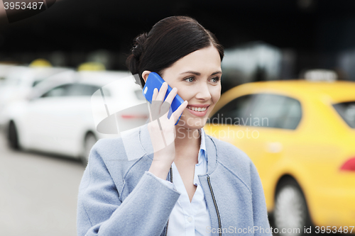Image of smiling woman with smartphone over taxi in city