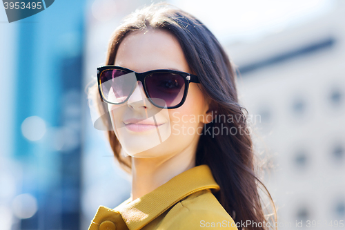 Image of smiling young woman with sunglasses in city