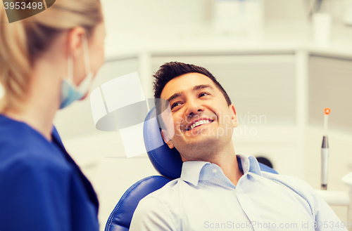 Image of female dentist with happy male patient at clinic