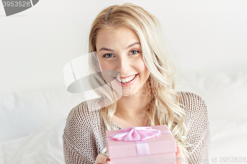 Image of happy young woman with gift box at home