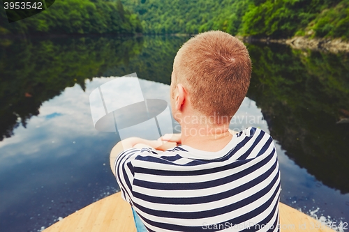 Image of Vacation trip on the river. Handsome man is sitting on the prow of the boat