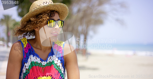 Image of Grinning woman in sunglasses and hat near ocean