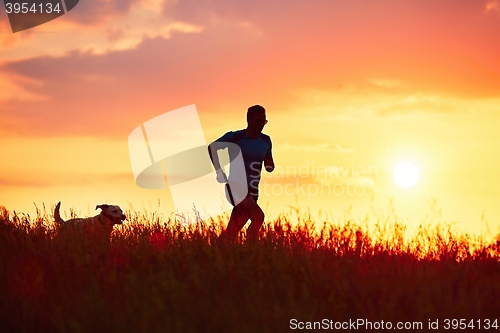 Image of Athletic runner with dog at the sunset