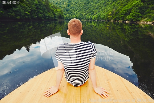 Image of Vacation trip on the river. Handsome man is sitting on the prow of the boat